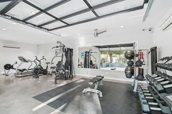 A spacious home gym with a variety of equipment including a treadmill, weights, and a bench. at The Viridian Apartments, Scottsdale, Arizona